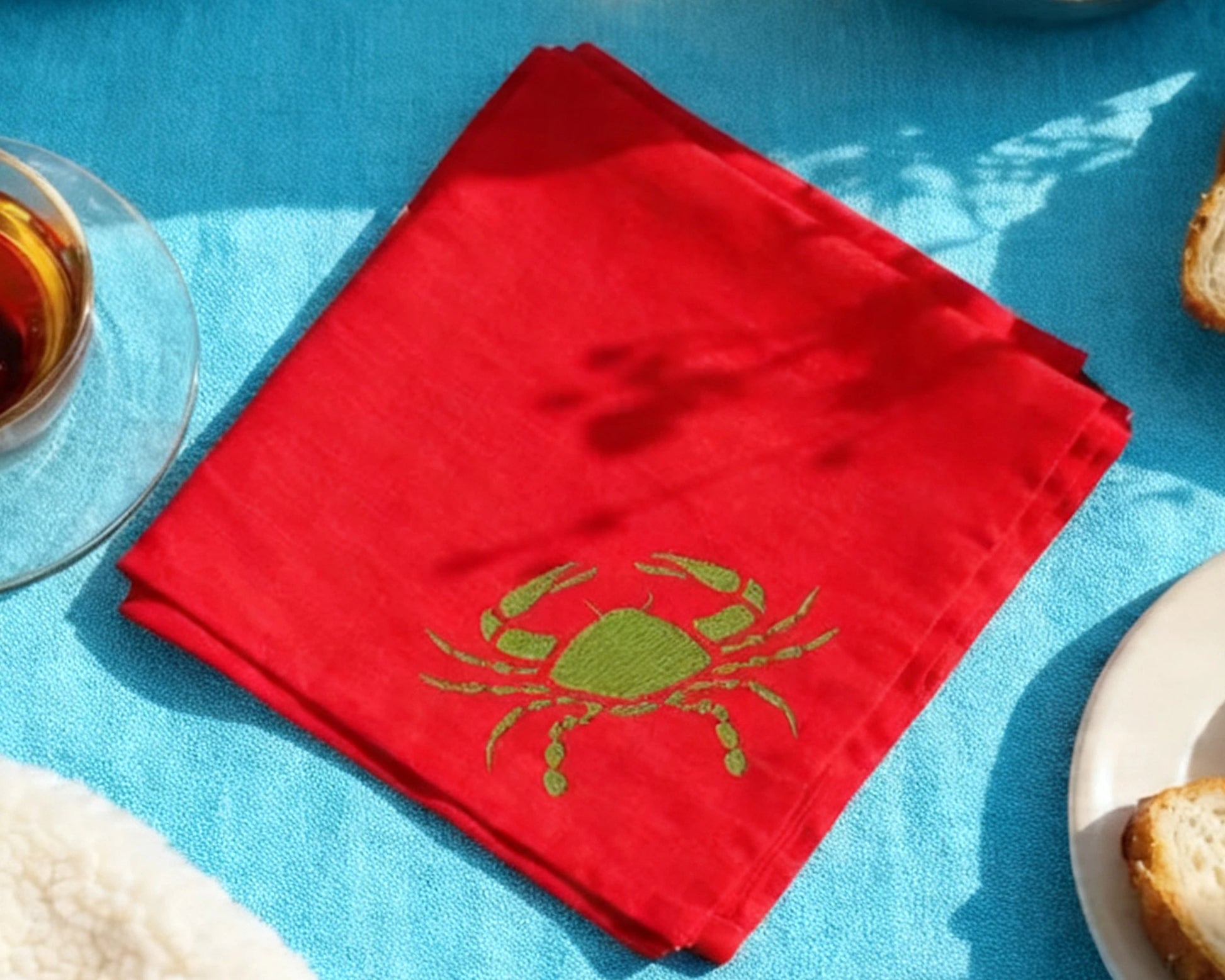 Red hanky with a green crab design on a blue tablecloth