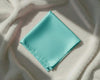Turquoise fabric square on a textured beige surface