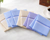 Set of folded handkerchiefs in various colors on a light surface with a cup of coffee in the background.