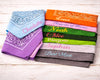 Set of colorful bandanas with embroidered names on a wooden surface