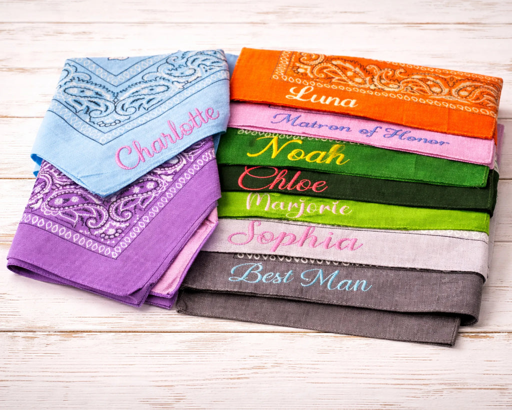 Set of colorful bandanas with embroidered names on a wooden surface