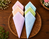 Set of colorful folded hanky on a woven basket with flowers in the background