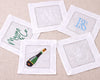 Set of embroidered cocktail napkins with various designs on a beige surface