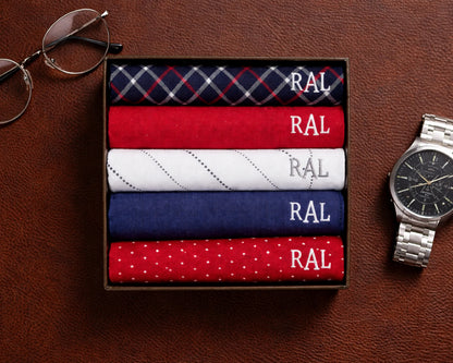 Set of folded HANKY with 'RAL' branding on a brown surface, next to eyeglasses and a watch.