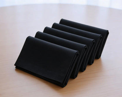 Set of folded black hanky on a table with flowers in the background