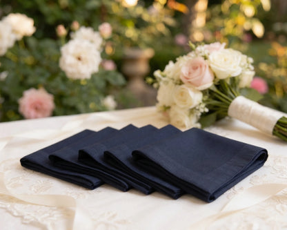 Set of folded black hanky on a table with flowers in the background