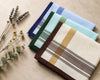 Set of folded cotton hanky with different patterns on a beige surface with dried plants.