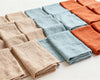 Set of folded hanky in beige, blue, and rust colors on a white background