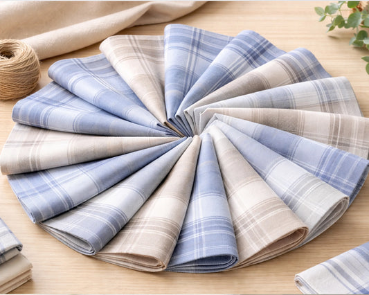 Set of folded plaid hankies in blue, beige, and gray on a wooden surface.