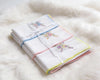 Set of folded white towels with colorful embroidery on a fluffy white surface
