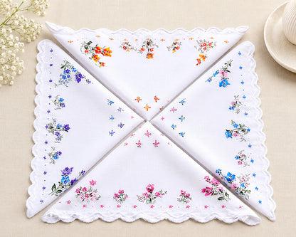 Set of four embroidered handkerchiefs with floral patterns on a beige surface.
