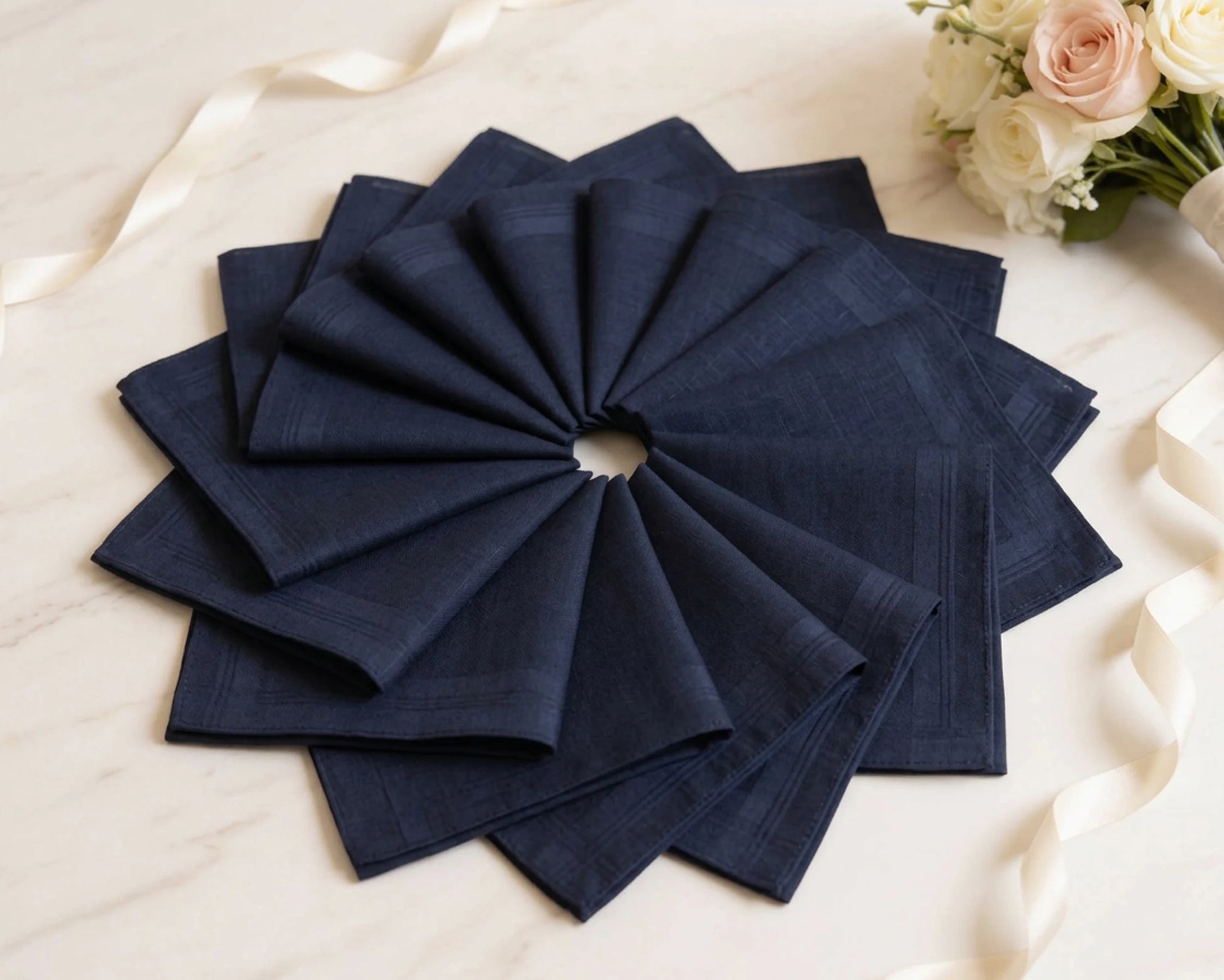 Set of navy blue hanky folded in a decorative pattern on a light background.