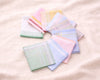 Set of pastel-colored handkerchiefs arranged in a circular pattern on a light background.