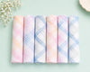 Set of pastel-colored plaid cotton  hanky on a light green background with small flowers.