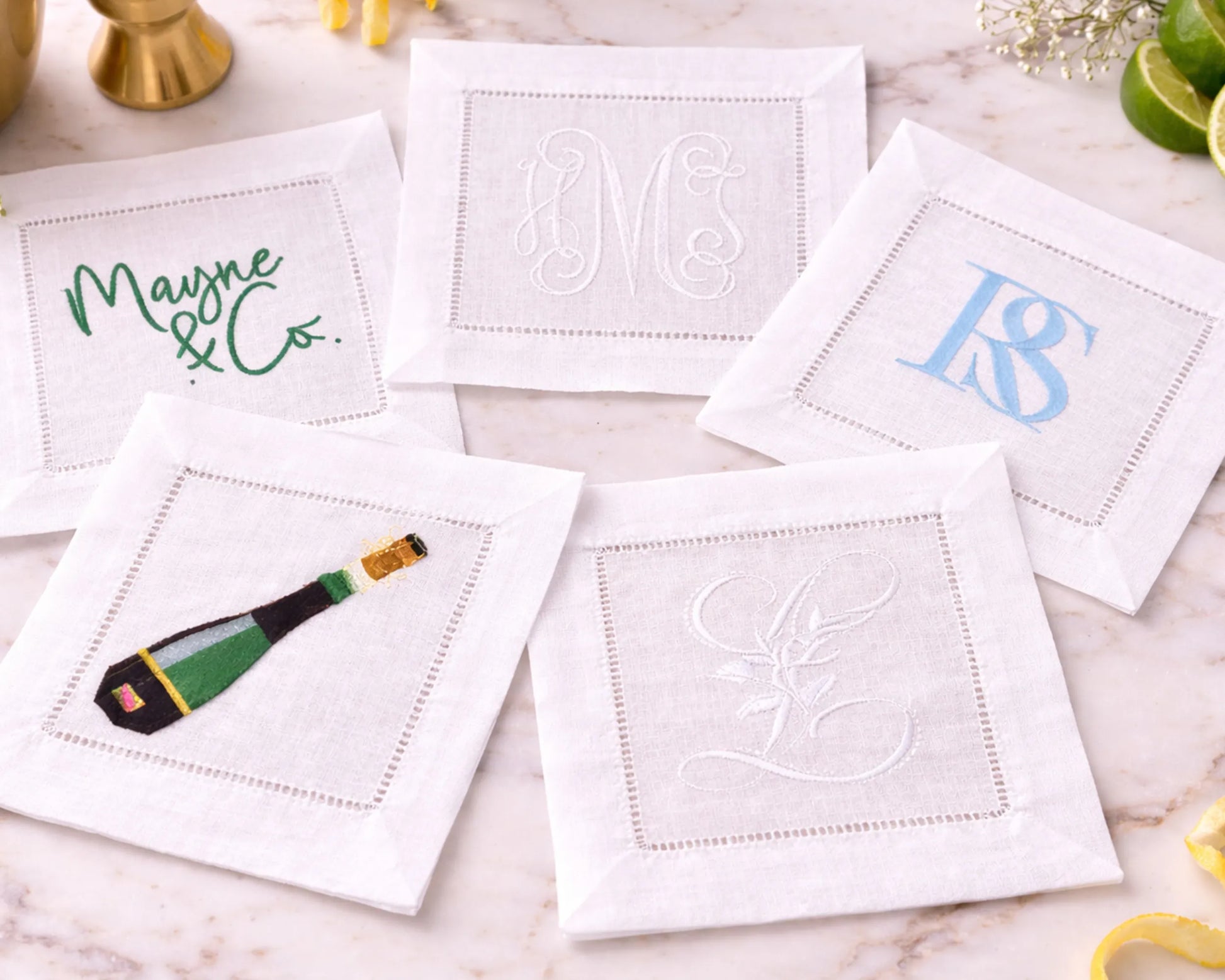 Set of personalized cocktail napkins with various designs on a marble surface.