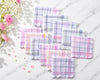 Set of plaid fabric hanky on a light wooden surface with flowers.
