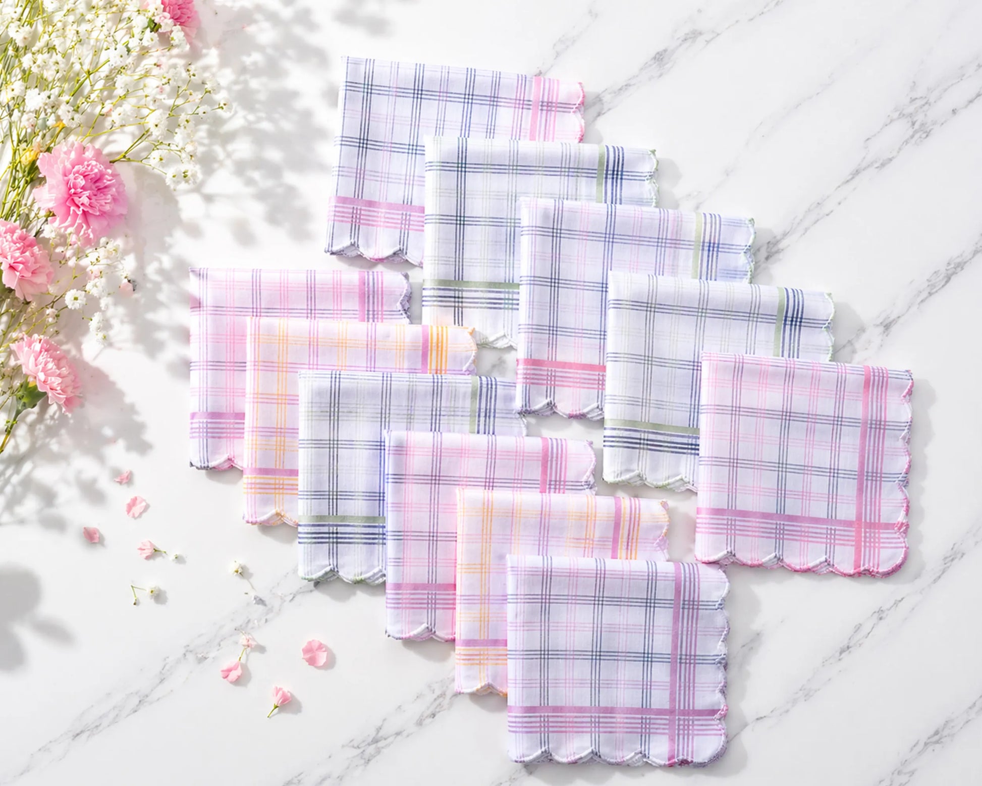 Set of plaid fabric hanky on a light wooden surface with flowers.