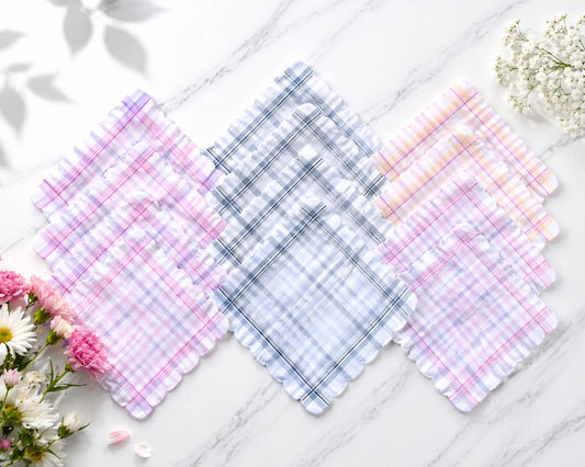 Set of plaid fabric swatches in pink, blue, and white on a marble surface with flowers.