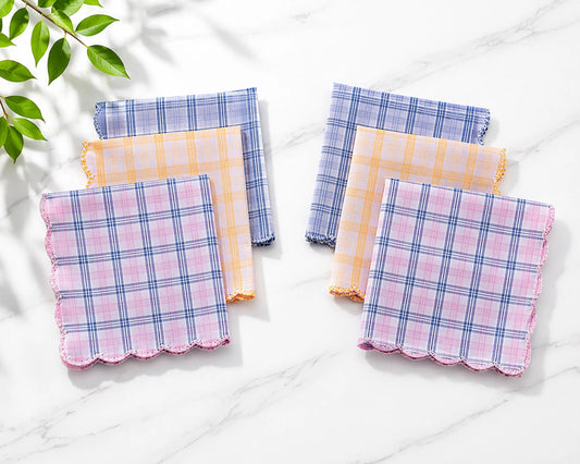 Set of plaid handkerchiefs on a white surface with a leafy branch in the corner.