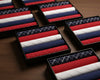 Set of red, white, and blue patterned hanky in black boxes on a wooden surface