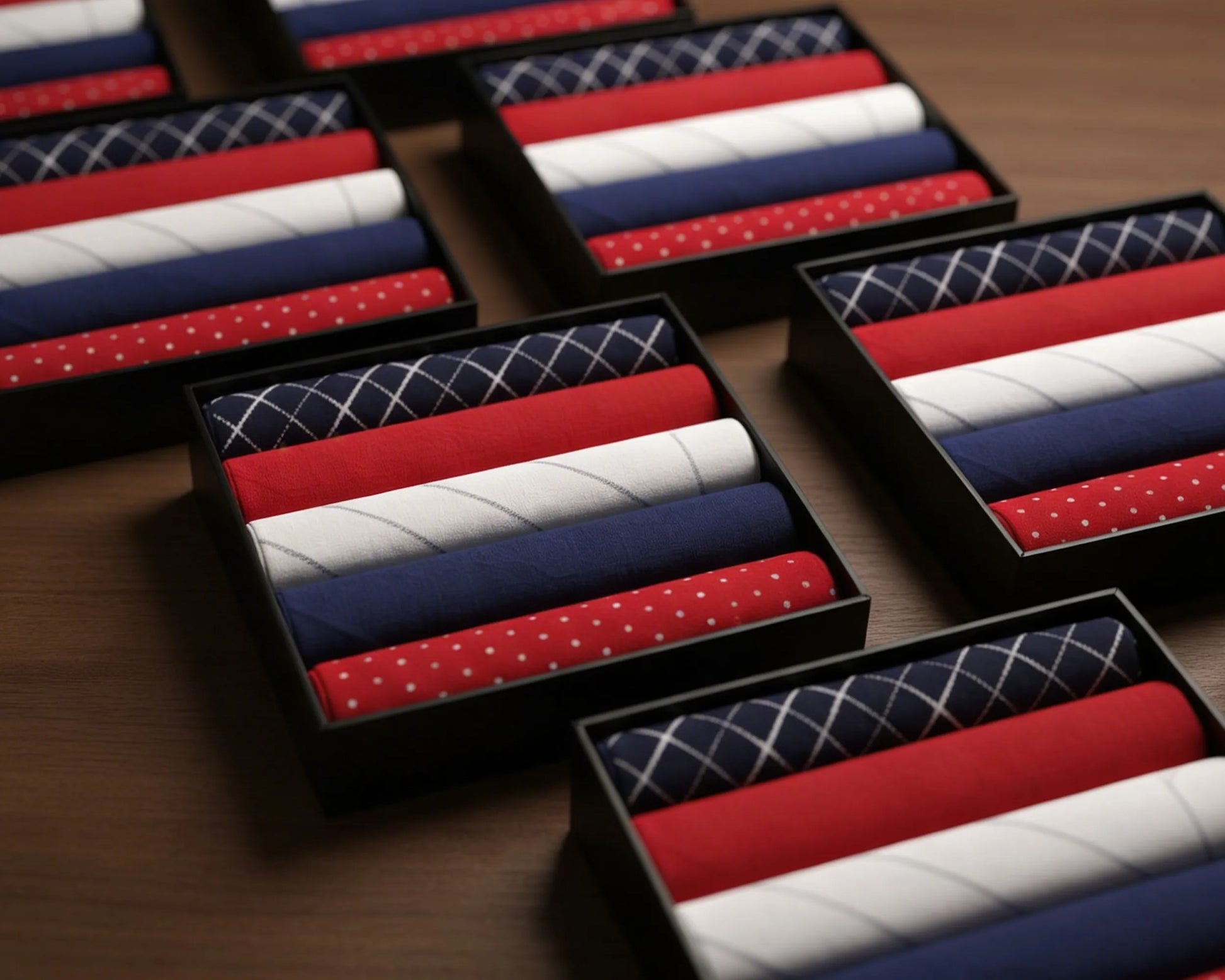 Set of red, white, and blue patterned hanky in black boxes on a wooden surface