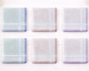 Set of six plaid handkerchiefs in pastel colors on a white wooden background