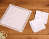 Set of white lace trimmed handkerchiefs on a wooden surface