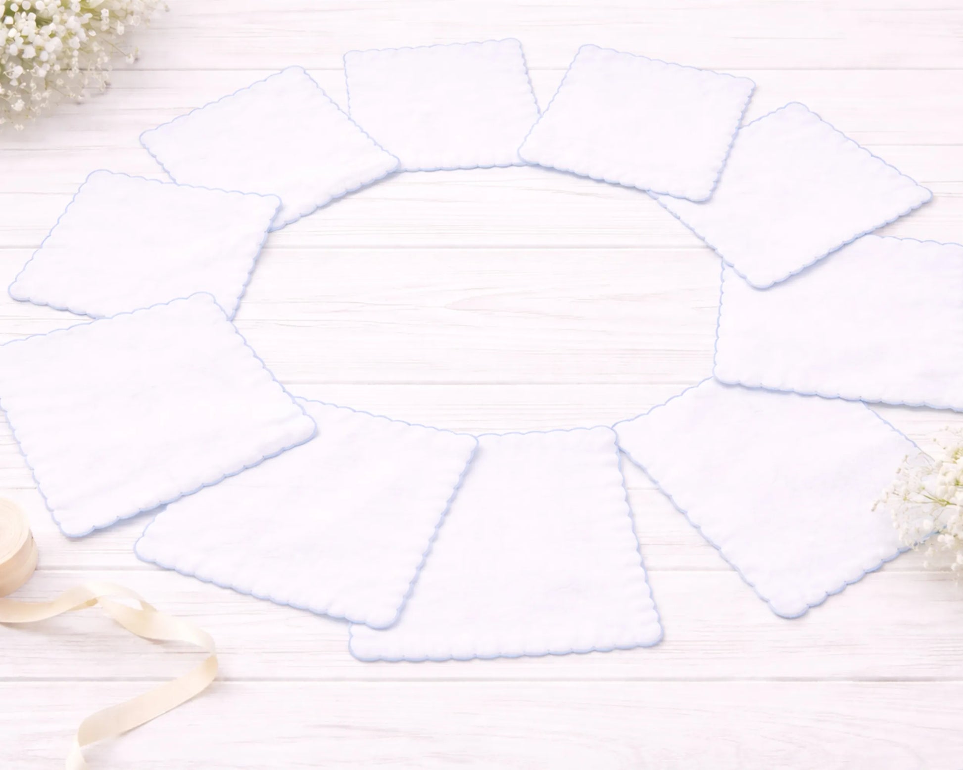 Set of white hanky on a light wooden surface with decorative elements.