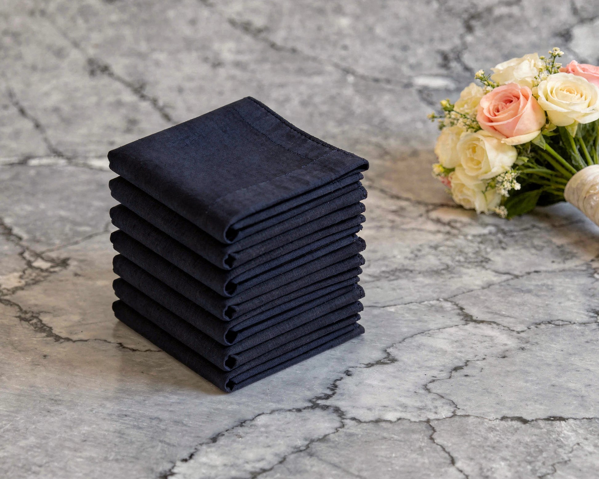 Stack of black hankie on a marble surface with flowers in the background