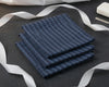 Stack of blue checkered hanky on a dark surface with white ribbons.