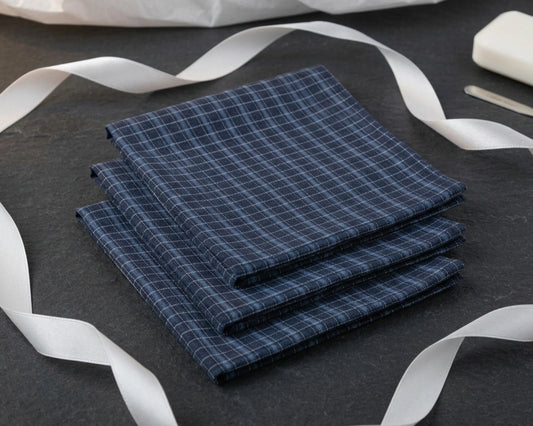 Stack of blue checkered hanky on a dark surface with white ribbons.