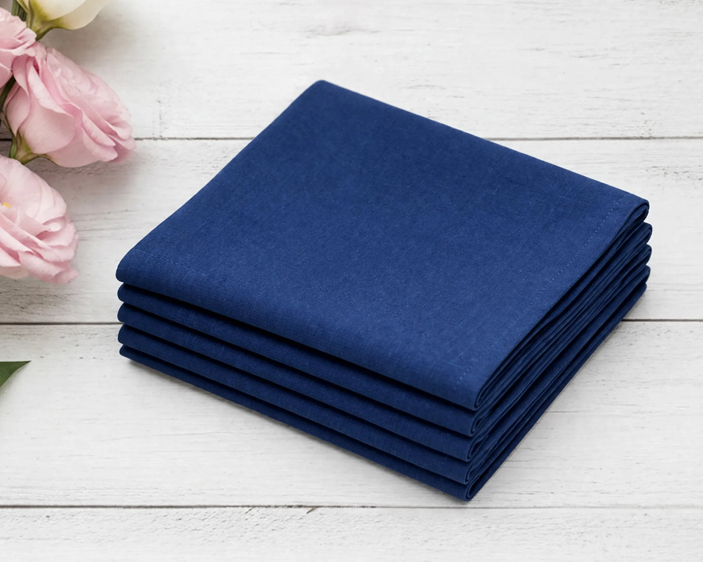 Stack of blue hanky on a white wooden surface with pink flowers.