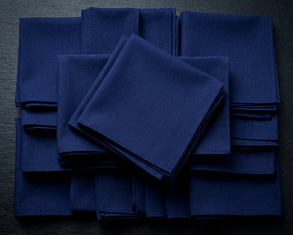 Stack of blue napkins on a beige surface with green leaves.