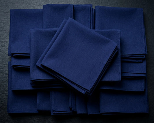 Stack of blue napkins on a beige surface with green leaves.