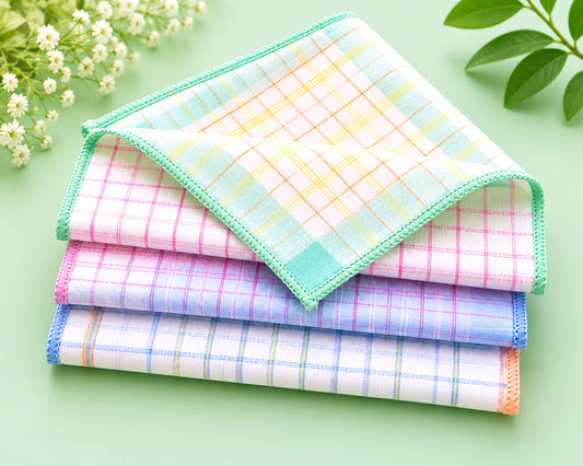 Stack of colorful checkered handkerchiefs on a light green background with flowers and leaves.