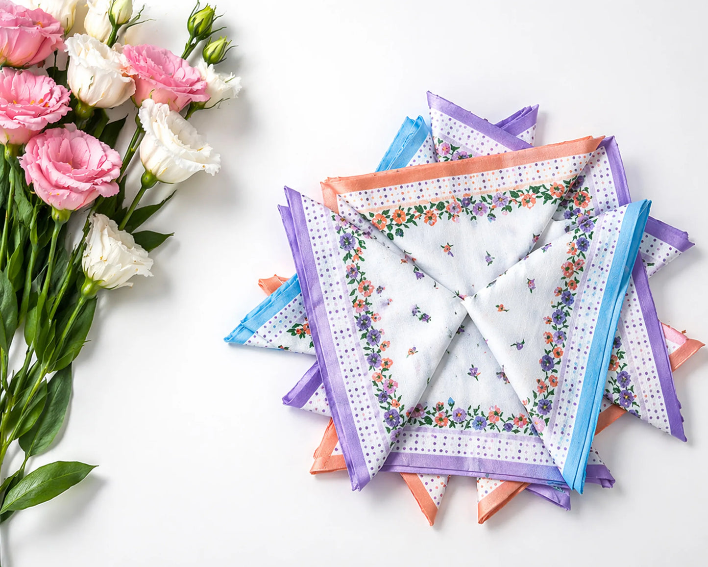 Stack of floral-patterned handkerchiefs with a bouquet of flowers on a white background