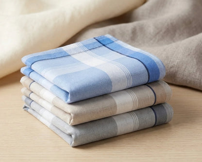 Stack of folded checkered hanky in blue, beige, and gray on a wooden surface.