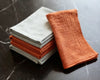 Stack of folded orange and gray cloths on a marble surface