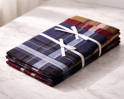 Stack of plaid hanky bundles tied with white ribbon on a marble surface