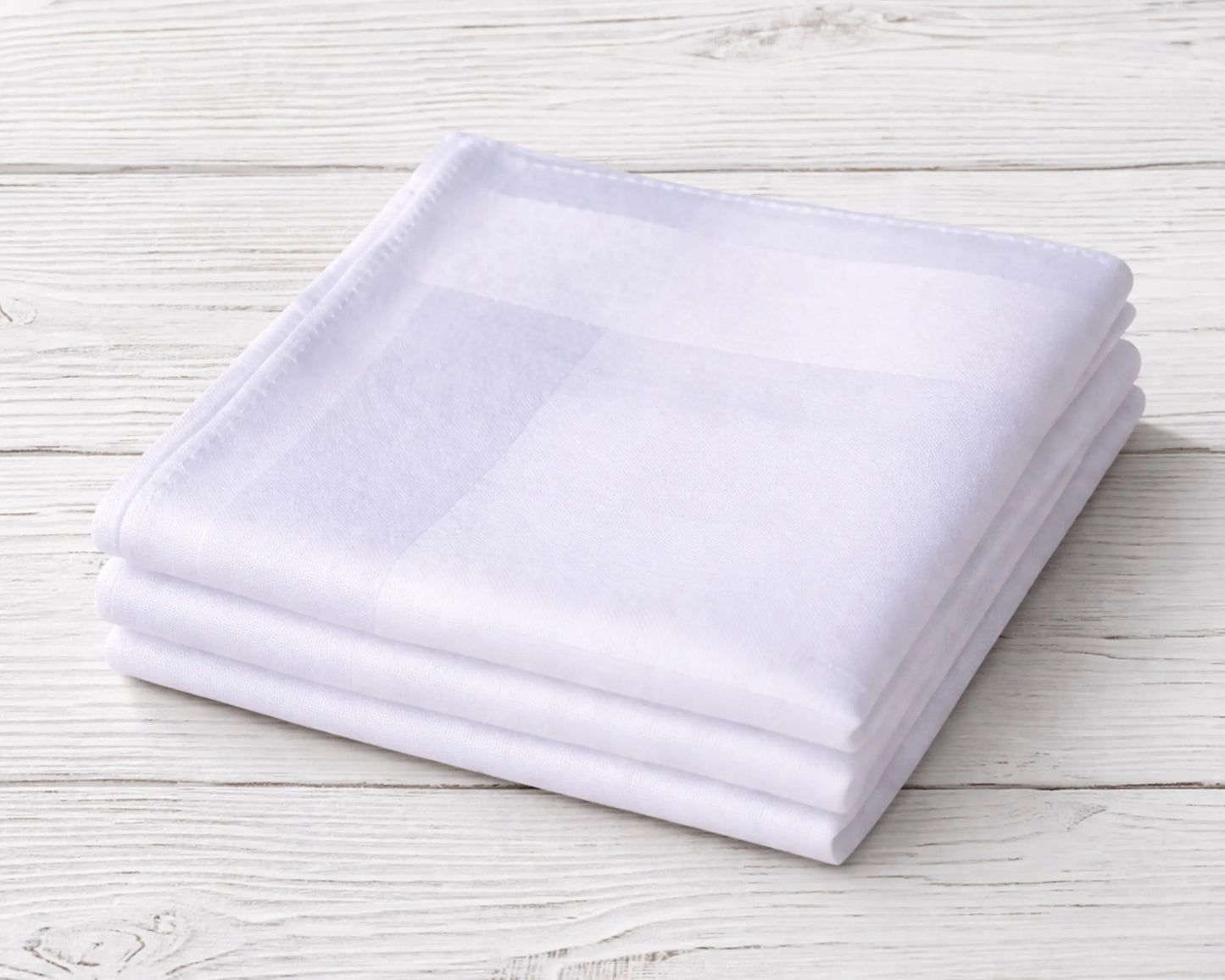 Stack of white folded towels on a light wooden surface