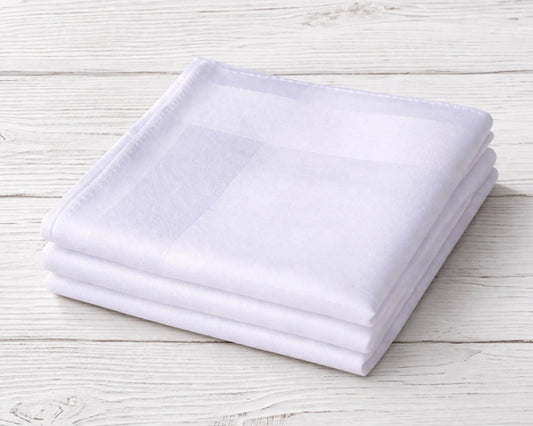 Stack of white folded towels on a light wooden surface