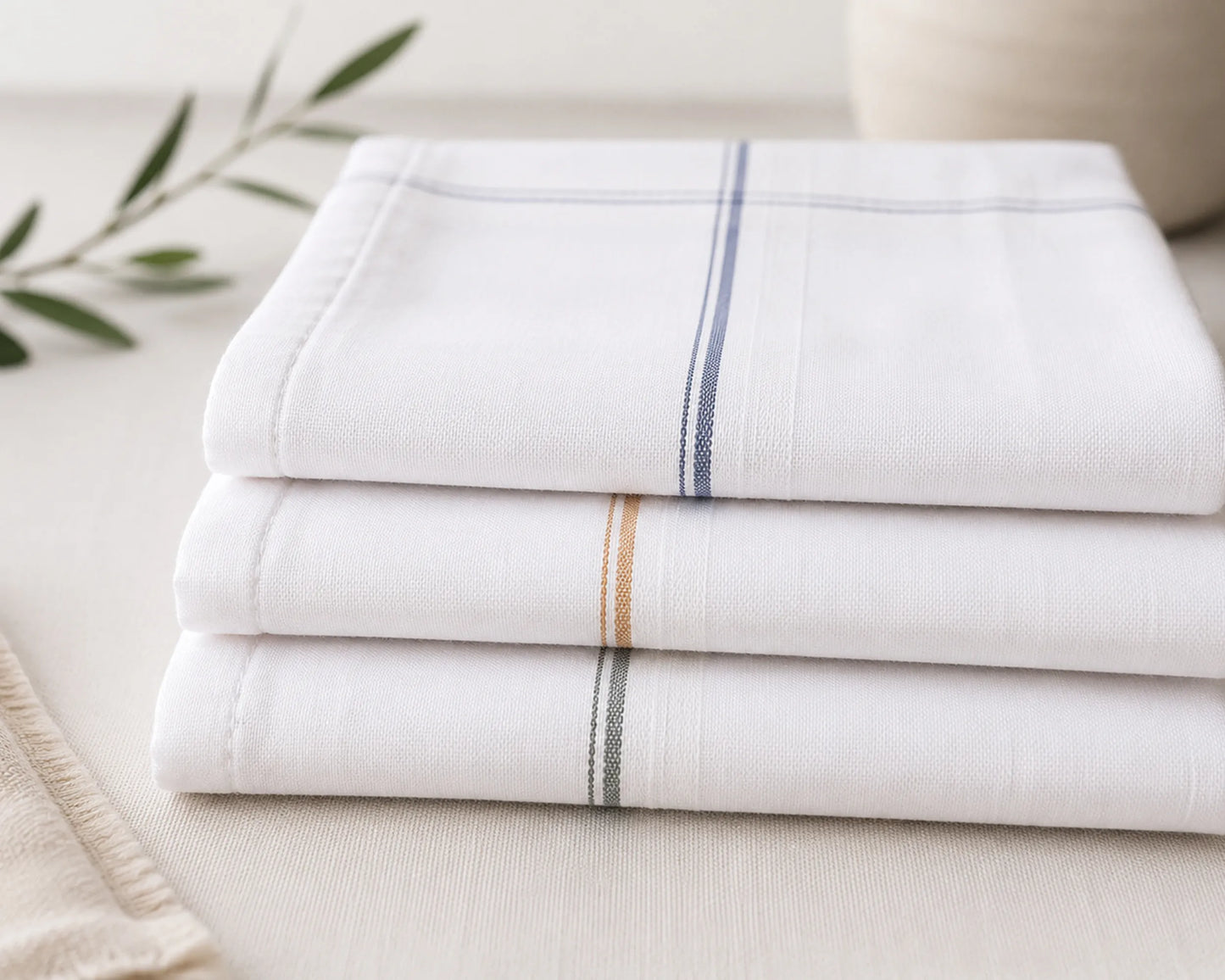 Stack of white hanky with thin stripes on a light surface