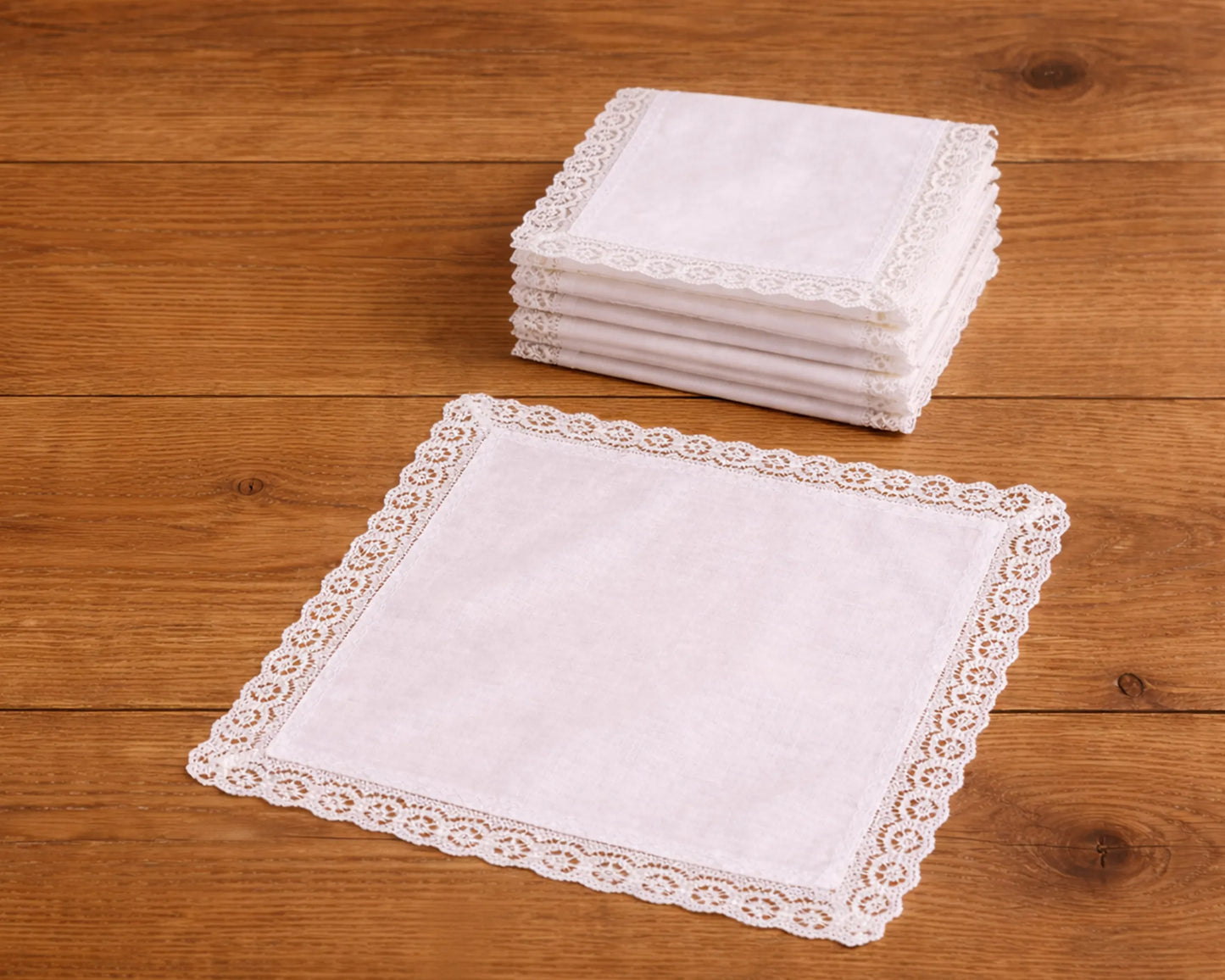 Stack of white lace-trimmed handkerchiefs on a wooden surface