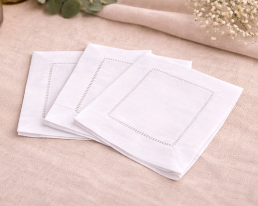Stack of white napkins on a beige surface with floral decorations.