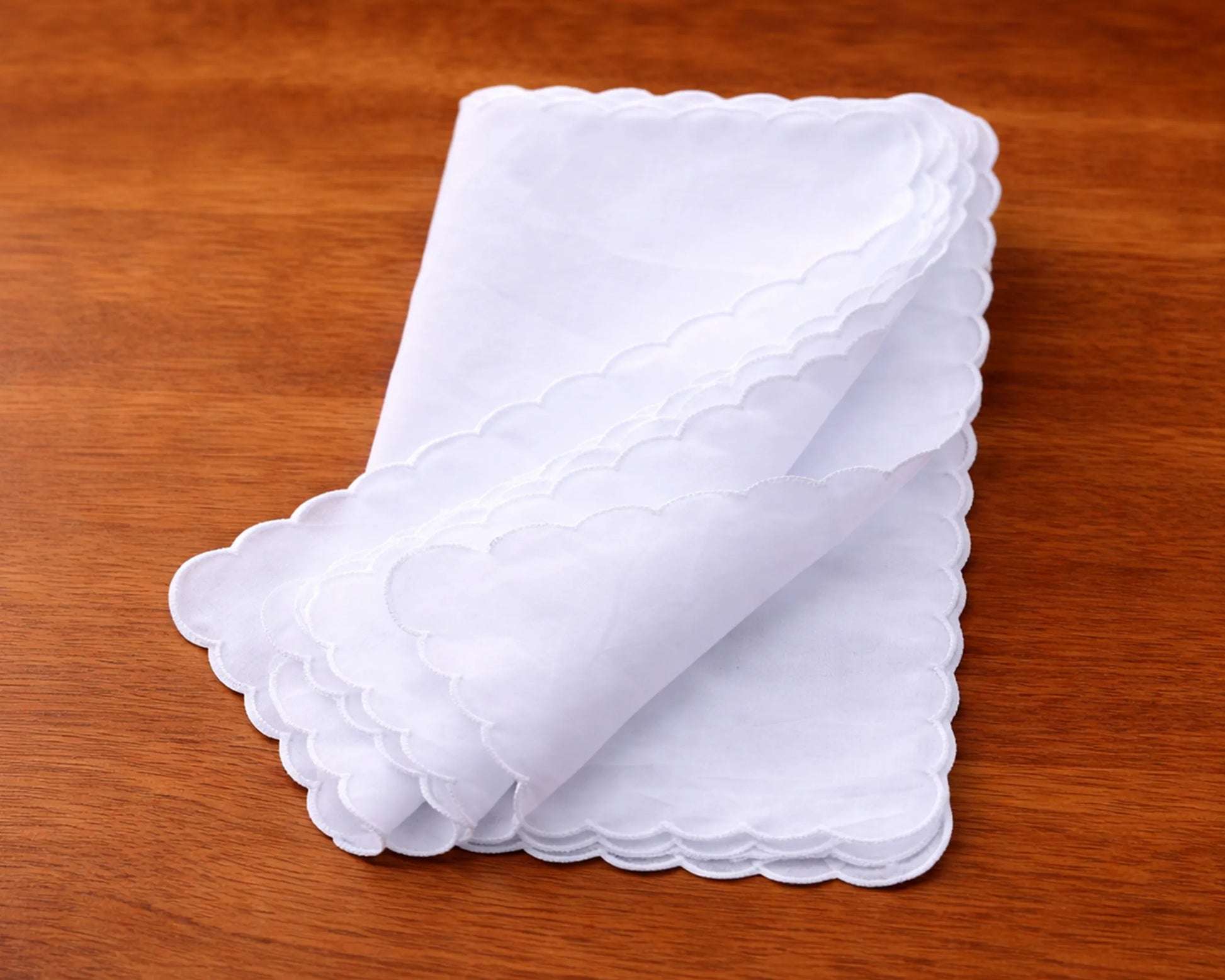 Stack of white scalloped-edged hanky on a wooden surface