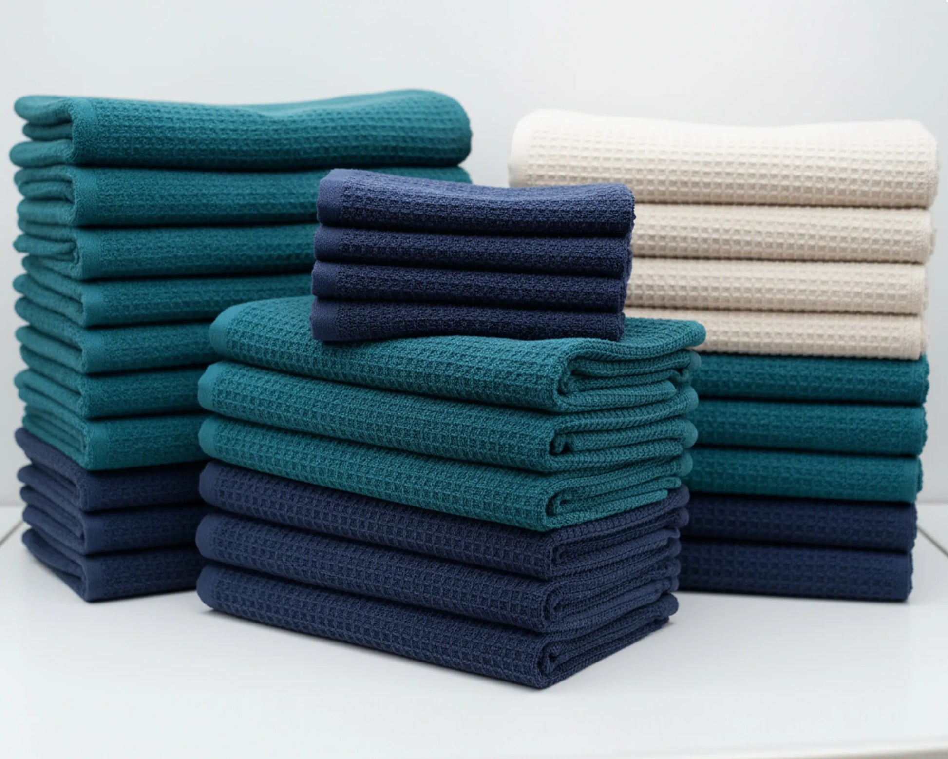 Stacks of folded towels in teal, navy, and white on a white background