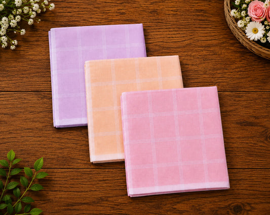 Three checkered hanky in purple, peach, and pink on a wooden surface with flowers.