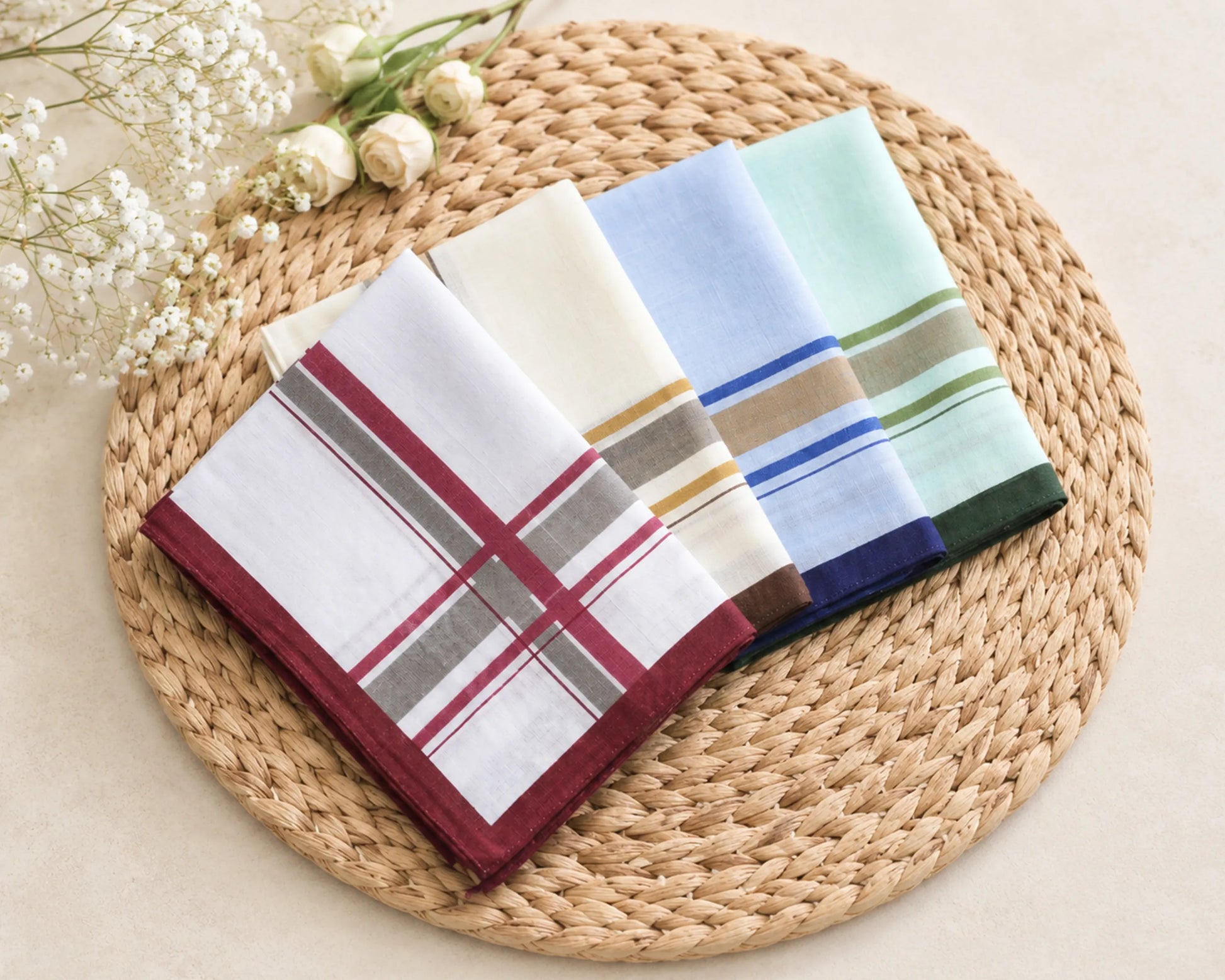 Three colorful handkerchiefs on a woven mat with flowers in the background