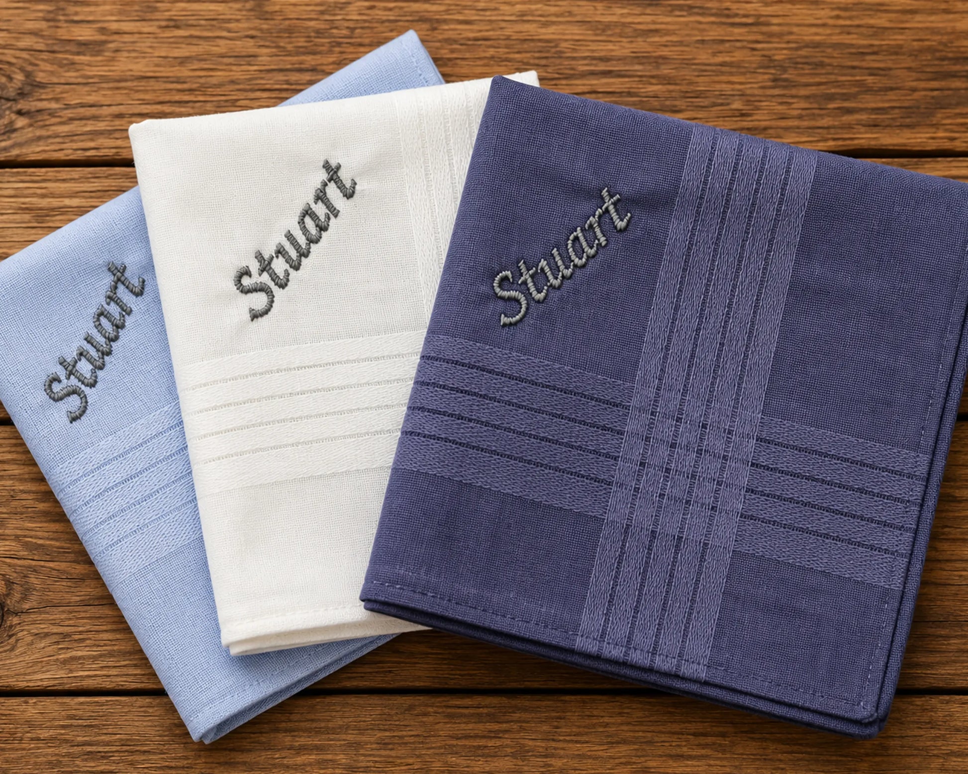 Three embroidered hanky with 'Stuart' on a wooden surface