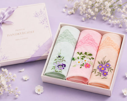 Three floral embroidered handkerchiefs in a box on a purple background with flowers.